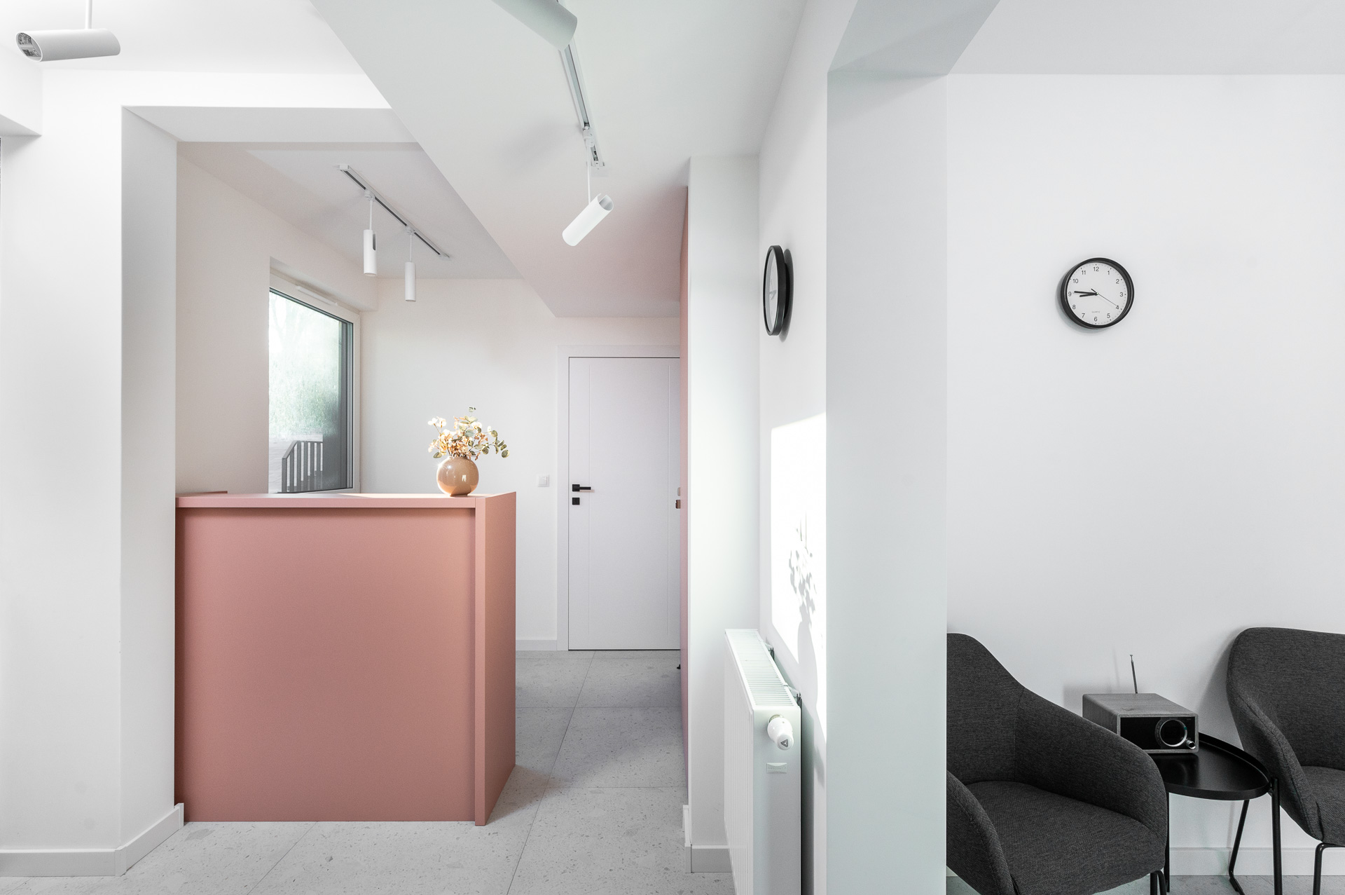 Waiting room with a pink reception desk and armchairs for clients, Płaszowska 25, Kraków